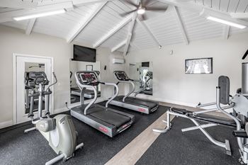 A gym with treadmills, elliptical machines, and a fan.